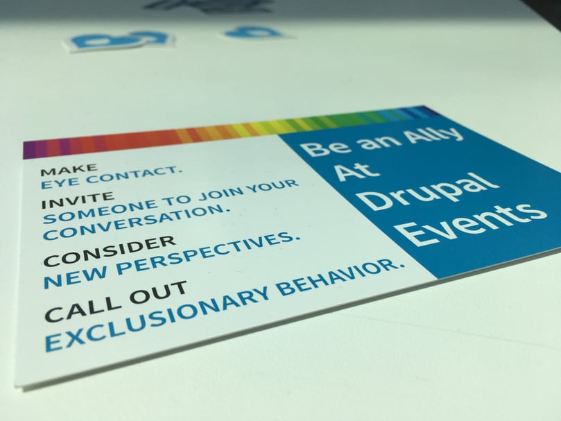 Flyer put on a table with the text "Make eye Contact. Invite someone to join the conversation. Consider new perspectives. Call out exclusionary behavior. Be an ally at Drupal events."