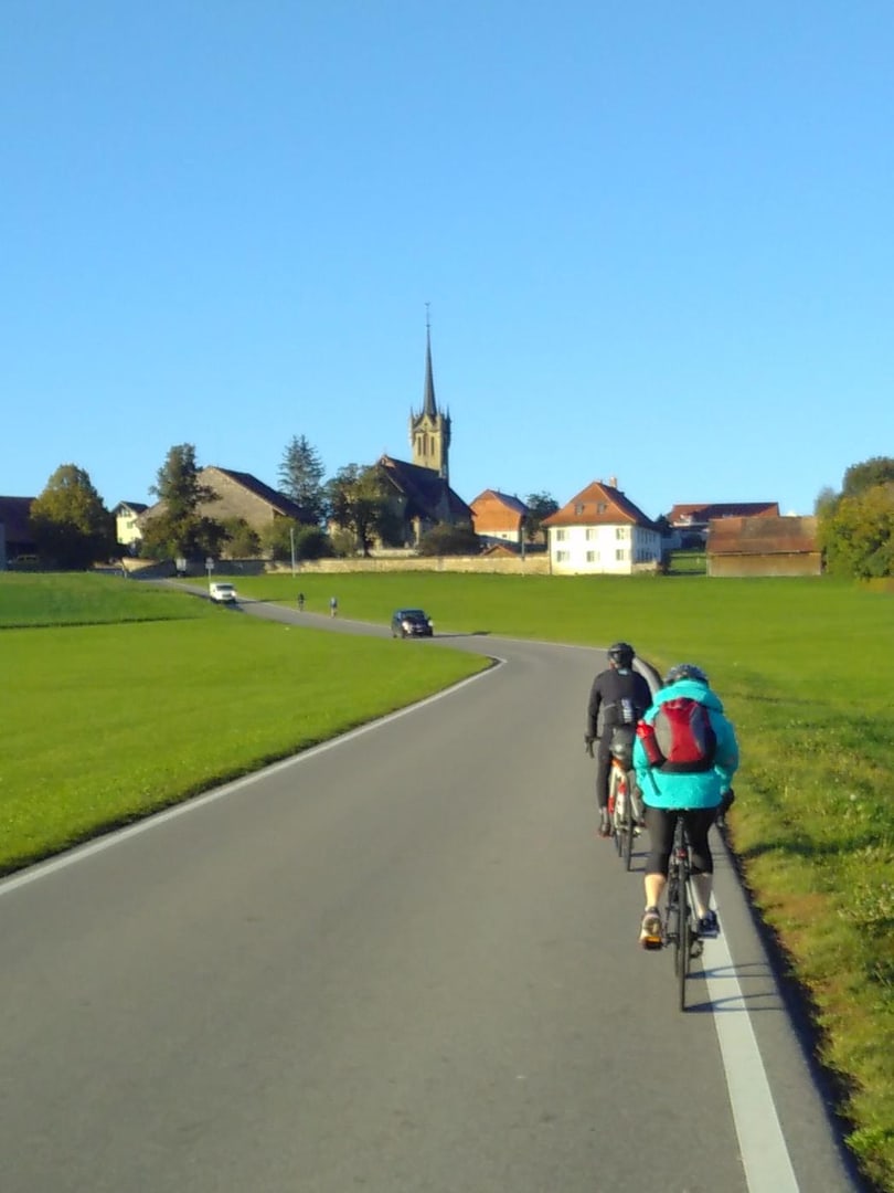 two biking Liipers in front of a sunny landscape with a church